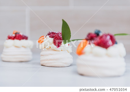Pavlova meringue cake with cream and small fruits 47051034