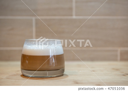 multilayer coffee or cappuccino in a glass cup on wooden table 47051036