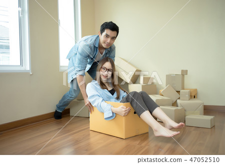 Happy couple having fun young pushing on cardboard 47052510