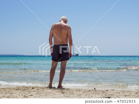 old man lying on the sand at the beach 47052933