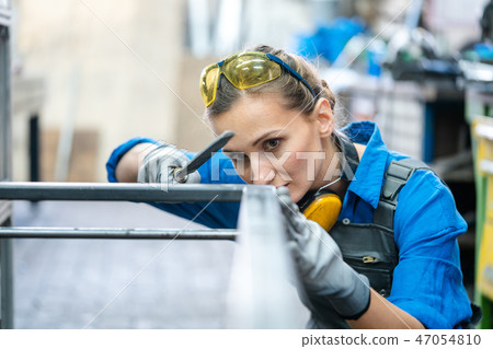 Woman metalworker checking the accuracy of her work 47054810