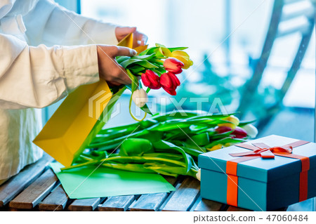 wrapping beautiful tulips near gift box on wooden table wrapping beautiful tulips near gift box on wooden table 47060484