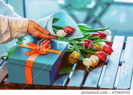 wrapping beautiful tulips near gift box on wooden table wrapping beautiful tulips near gift box on wooden table 47060500