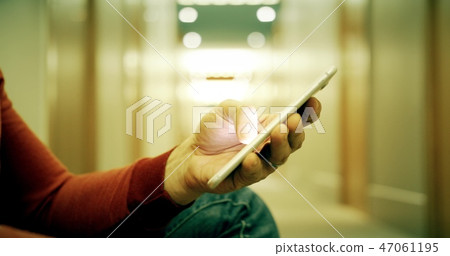Man in casual clothes uses his smartphone in the hotel hallway 47061195