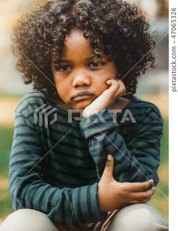Unhappy little african american kid in the park. Unhappy little african american kid in the park. 47065326