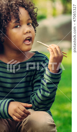 Happy african american child eating snack stick. Happy african american child eating snack stick. 47065327