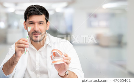 Dentist with toothbrush, focus at toothbrush. Dentist with toothbrush, focus at toothbrush. 47065401