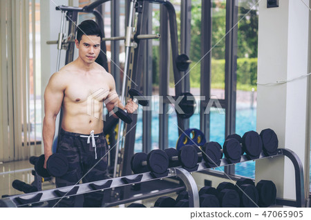 Muscular man bodybuilder training with dumbbells. Muscular man bodybuilder training with dumbbells. 47065905