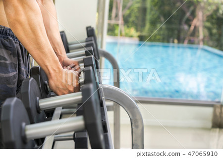 Muscular man bodybuilder training with dumbbells. Muscular man bodybuilder training with dumbbells. 47065910