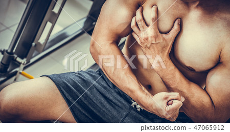 Muscular man touching his chest in fitness center. Muscular man touching his chest in fitness center. 47065912