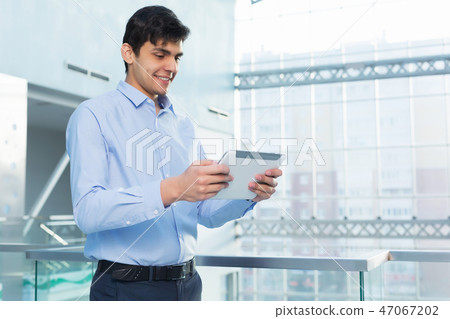 Businessman leaning on balcony railings Businessman leaning on balcony railings 47067202