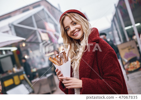 Close-up of young blonde woman eatting churros Close-up of young blonde woman eatting churros 47067835