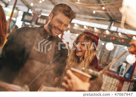 Close-up of young couple are drinking mulled wine at the street food market. 47067947