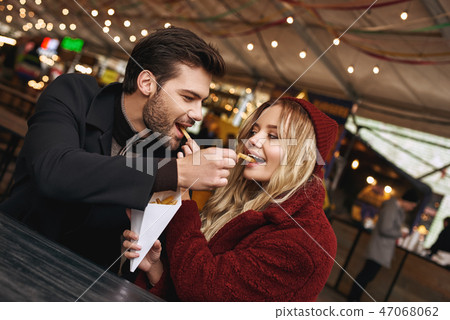 Close-up of young couple are eating french fries at the street food market. 47068062