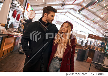 Happy young couple walking around street food market. Blurred people at photo Happy young couple walking around street food market. Blurred people at photo 47068082