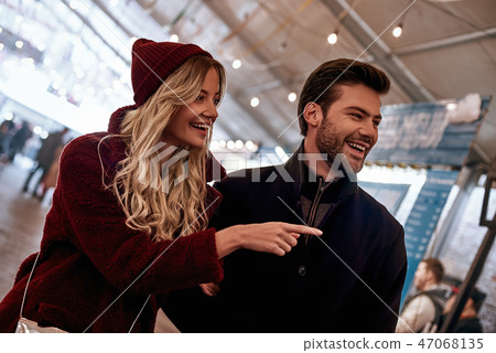 She shows something. Happy young couple walking around street food market. She shows something. Happy young couple walking around street food market. 47068135