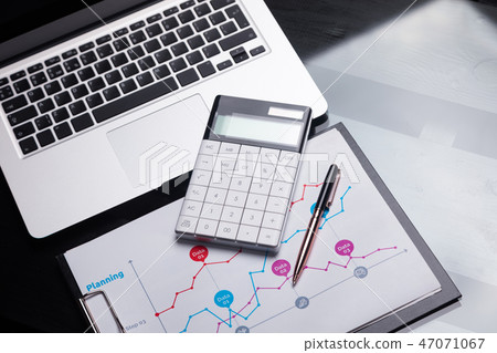 Modern calculator is on a laptop and on a sheet with a graph Modern calculator is on a laptop and on a sheet with a graph 47071067