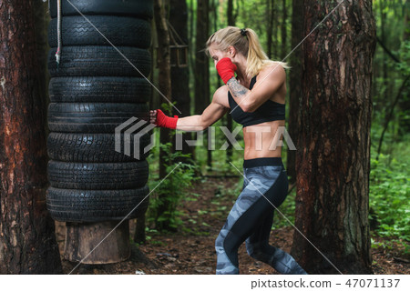 Woman boxer doing uppercut kick working out outdoors. 47071137