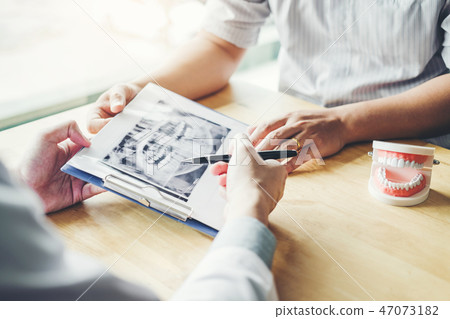 Dentist talking to male patient and presenting 47073182