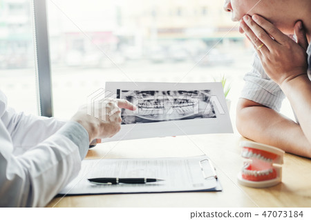 Dentist talking to male patient and presenting  47073184