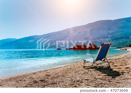 Blue sunchair on picturesque pebble beach, Kefalonia island, Greece. Travel relax vacation concept Blue sunchair on picturesque pebble beach, Kefalonia island, Greece. Travel relax vacation concept 47073699