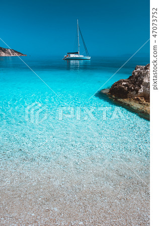 Lonely white sailing catamaran boat drift on calm sea surface. Pure azure clean blue lagoon with Lonely white sailing catamaran boat drift on calm sea surface. Pure azure clean blue lagoon with 47073752