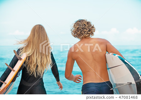 Surfers at the beach- Smiling couple of surfers walking on the beach and having fun in summer 47081468