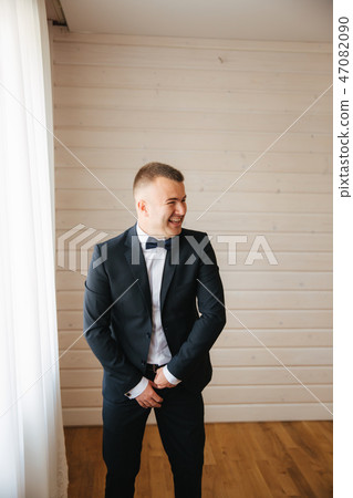 Young groom dressed in his home. Handsome man in wedding suit smile Young groom dressed in his home. Handsome man in wedding suit smile 47082090