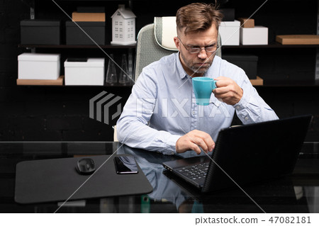 Serious businessman working on laptop and drinking coffee 47082181