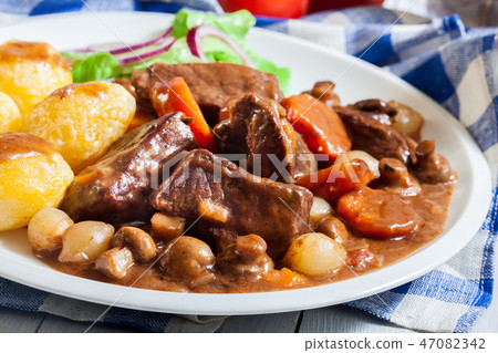 Beef Bourguignon stew served with baked potatoes Beef Bourguignon stew served with baked potatoes 47082342
