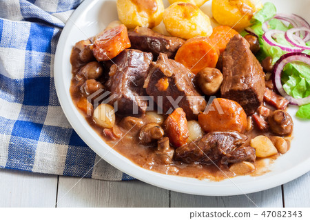 Beef Bourguignon stew served with baked potatoes Beef Bourguignon stew served with baked potatoes 47082343