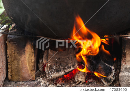 Black cauldron stands on a bonfire. Outdoor Black cauldron stands on a bonfire. Outdoor 47083690