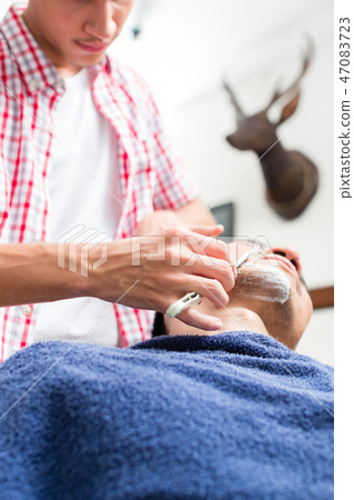 Man getting shaved from barber 47083723