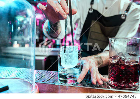 Expert barman is making cocktail at night club. 47084745