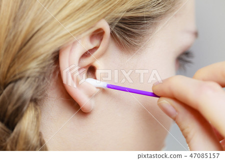 Woman cleaning ear with cotton swabs closeup Woman cleaning ear with cotton swabs closeup 47085157