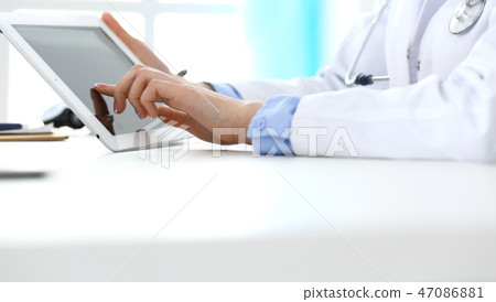 Woman doctor using tablet computer while sitting in hospital office closeup. Healthcare, insurance 47086881