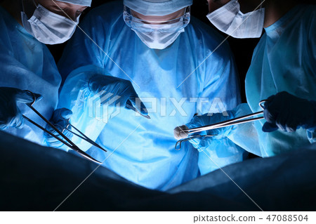 Group of surgeons in masks performing operation. Medicine, surgery and emergency help concepts Group of surgeons in masks performing operation. Medicine, surgery and emergency help concepts 47088504