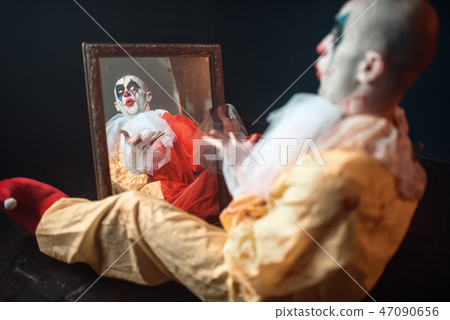 Bloody clown with crazy eyes sitting at the mirror Bloody clown with crazy eyes sitting at the mirror 47090656
