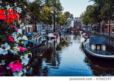 Bright flowers on a bridge over a beautiful tree-lined canal in the centre of Amsterdam, Netherlands 47092547