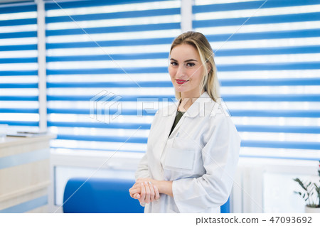 Portrait of young woman doctor with white coat standing in hospital Portrait of young woman doctor with white coat standing in hospital 47093692