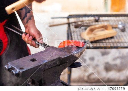 Blacksmith working on the anvil, making a horseshoe. 47095259