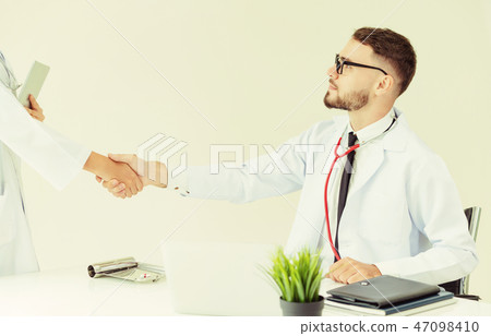 Doctor at hospital shakes hand with another doctor 47098410