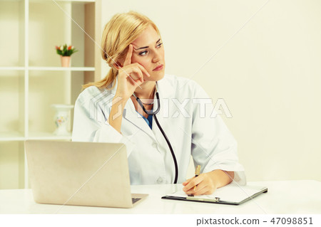 Serious doctor working in hospital office. 47098851