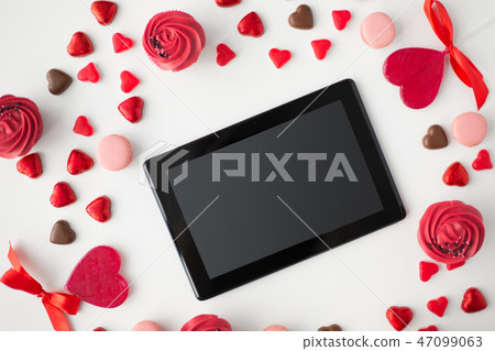 close up of tablet pc and sweets on valentines day close up of tablet pc and sweets on valentines day 47099063