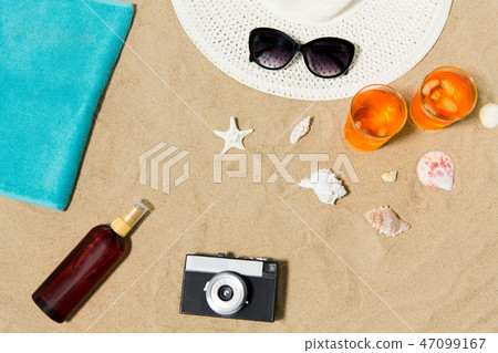 drinks, hat, camera and sunglasses on beach sand drinks, hat, camera and sunglasses on beach sand 47099167