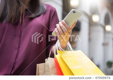 Woman look at mobile phone with paperbags in the mall while enjo 47099978