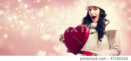 Young woman holding a big heart gift box 47100268