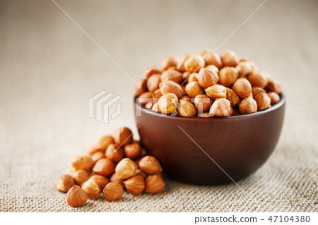 Peeled hazelnuts in a wooden, dark brown cup Peeled hazelnuts in a wooden, dark brown cup 47104380