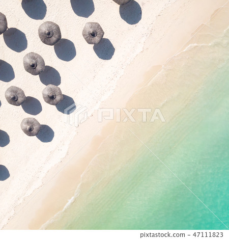 Aerial view of amazing tropical white sandy beach with palm leaves umbrellas and turquoise sea. Aerial view of amazing tropical white sandy beach with palm leaves umbrellas and turquoise sea. 47111823