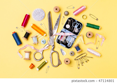 Composition with threads and sewing accessories - scissors, centimeter, pins on yellow background. 47114801